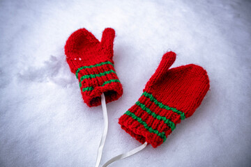 Children's red knitted mittens on the snow. Winter time.