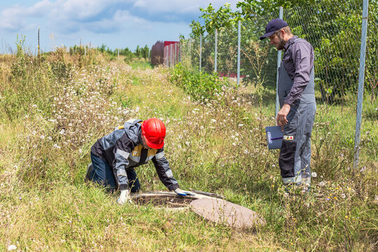 Workers inspect utility infrastructure, checking the meter and pipes in a water well in a rural area