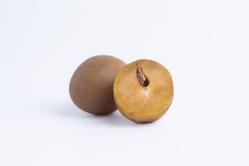 Whole and half sapodilla fruit isolated on white background, chiku, cross section shows brown sweet pulp and seed, healthy tropical food.
