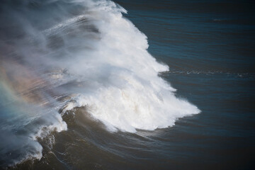Welle mit Regenbogen am Nordstrand von Nazare