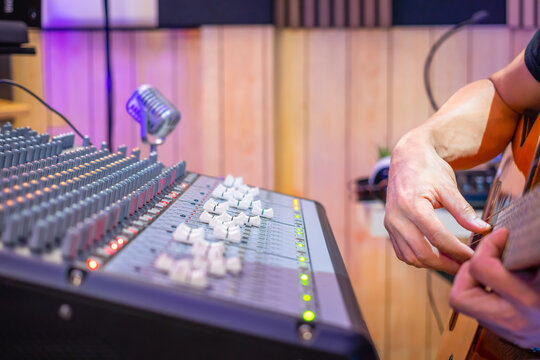 close up male musician hands playing acoustic guitar in home studio, recording concept. - Powered by Adobe