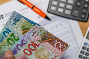 Taxes and financial settlements in New Zealand. New Zealand dollar, calculator, and tax form. Financie and business concept. Tax return. Financial background. Close up.