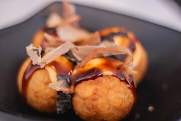 Octopus takoyaki, fried dough balls filled with octopus, traditionally sprinkled with bonito shavings, topped with takoyaki sauce, popular Japanese street food
