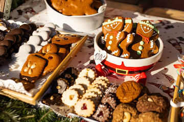 Assortment of gingerbread figures and other christmas cookies displayed on a market stall table,...