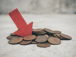 Red arrow pointing downward near tarnished pennies signifying loss