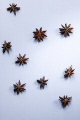 Top view of several star anise flowers arranged on a cool blue background, creating a winter or Christmas-themed composition with a minimal and festive aesthetic.