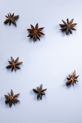 Top view of several star anise flowers arranged on a cool blue background, creating a winter or Christmas-themed composition with a minimal and festive aesthetic.