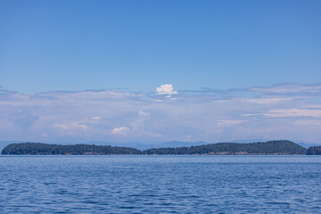 Calm Blue Waters and Forested Islands Under Expansive Cloudy Sky