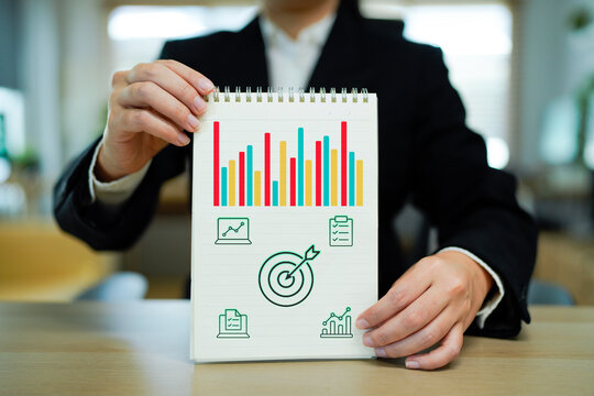 Businessman hand holding a note with growth bar chart and business strategy icons for future success target with arrows and growth chart, representing business success and goal achievement - Powered by Adobe