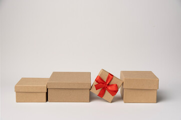 Cardboard box tied with red ribbon among craft boxes on white background, copy space