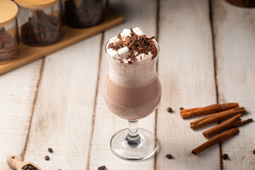 Delicate chocolate drink served in a glass with marshmallows and shaved chocolate on top
