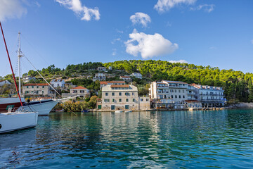 Fototapeta premium Coastal Harbor Village With Stone Buildings, Boats, And Calm Blue Water Reflections