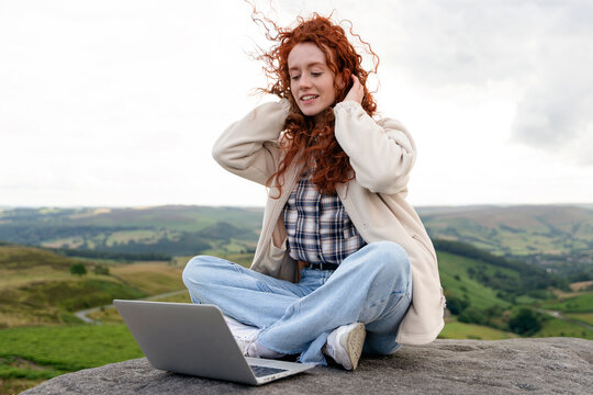 Woman enjoying nature while working on a laptop outdoors