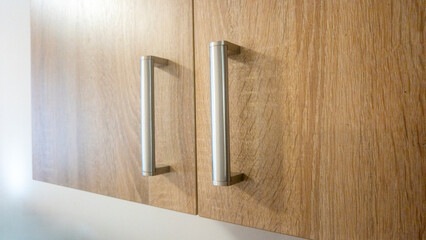 Metal handles on wooden cabinet doors create a modern touch in a kitchen interior, providing ease of access and functionality in home design aesthetics.