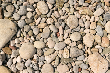 Round natural pebbles creating peaceful tone and natural pattern. Coastal view with earthy stone texture, pebbles organized randomly by nature. Pebbles show organic design.