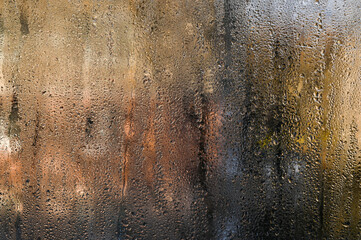 wet glass. Tiny beads of moisture decorate fogged window, background. Some drops slide slowly downward, leaving ephemeral trails on glass. abstract backdrop wet glass