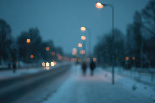Blurred snowy evening with glowing street lights, soft bokeh effect, winter atmosphere, silhouettes of people walking, peaceful urban scene, cold blue tones, serene mood