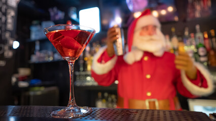 Santa Claus works at the bar making cocktails in a shaker.