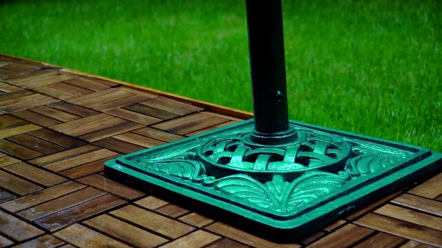 Composition of wooden parquet and grass in an outdoor setting during rainy weather. Focus and depth of field are selective. A romantic rainy landscape in the garden.