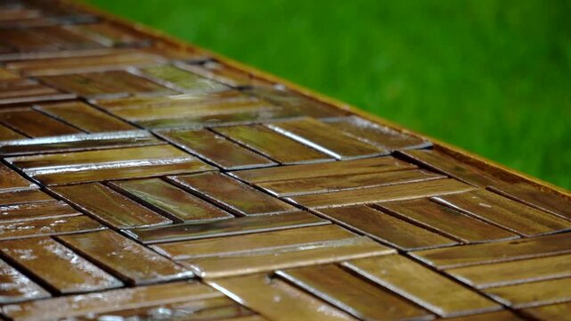 Composition of wooden parquet and grass in an outdoor setting during rainy weather. Focus and depth of field are selective. A romantic rainy landscape in the garden.