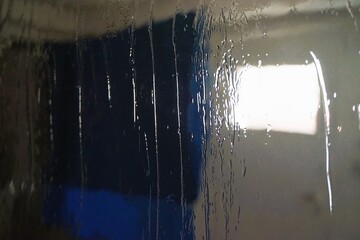 Abstraktes Motiv mit Glasscheibe vor Innenausstattung von Waschküche mit blauem Handtuch auf...