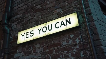 Illuminated yes you can lightbox sign on dark brick alley wall, motivational quote concept for personal inspiration and encouragement