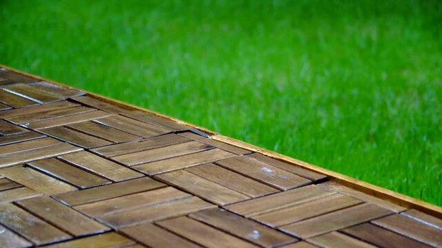 Composition of wooden parquet and grass in an outdoor setting during rainy weather. Focus and depth of field are selective. A romantic rainy landscape in the garden.