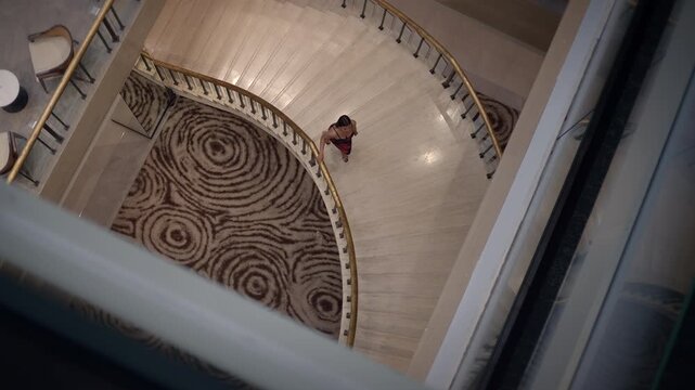 elegant hotel staircase, spiral staircase and patterned carpet in hotel lobby during evening