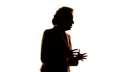 Silhouette of a confident female speaker delivering an engaging presentation on a brightly lit stage.
