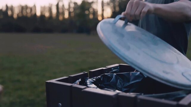 Close-up of plastic bottle being recycled in park bin outdoors