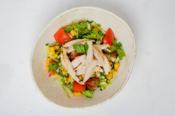 Colorful salad featuring grilled chicken, corn, cucumbers, and fresh herbs, served in a bowl