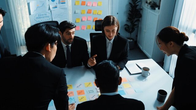 Top down aerial view of smart business man join meeting and present financial plan while diverse business people discuss and brainstorm marketing idea by using sticky notes at conference. Directorate.