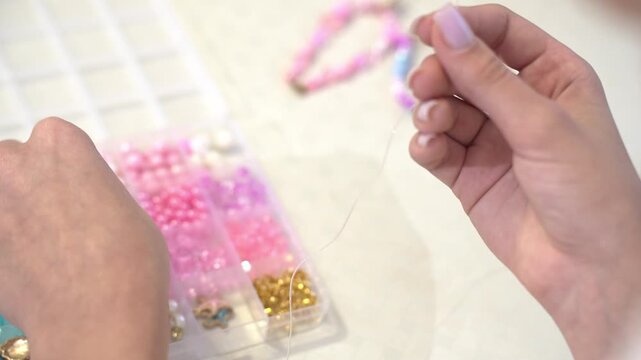 a girl is making a beaded bracelet