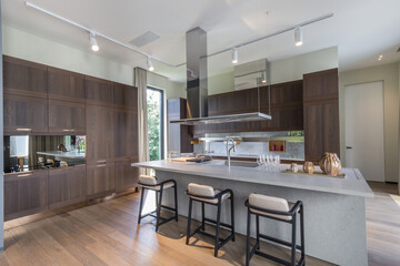 Bright and spacious kitchen featuring wooden cabinetry, stylish countertops, and an open layout. Large windows invite natural light into the warm, inviting space
