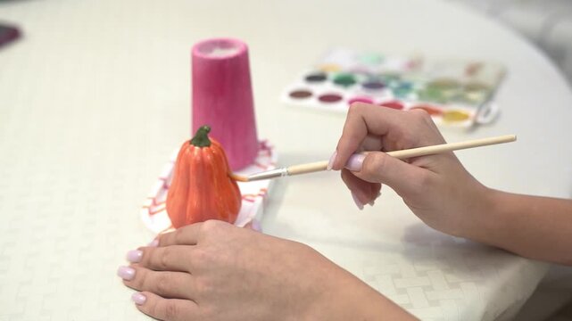 handicraft hobby girl painting a plaster pumpkin figurine