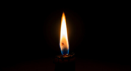 Close up of a single candle flame burning in complete darkness