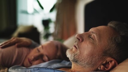 Husband facing inner struggles while lying beside sleeping wife, health concerns