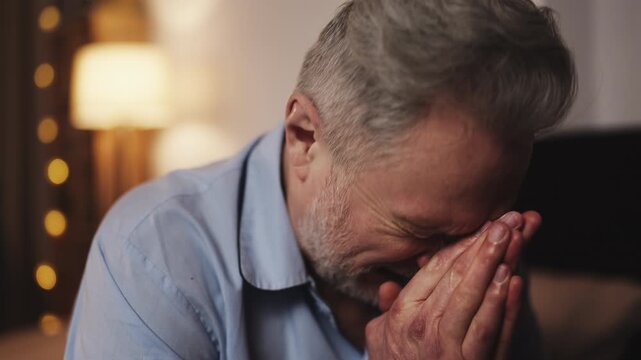 Sad man in his 50s thinking about health problems while sitting on bed alone