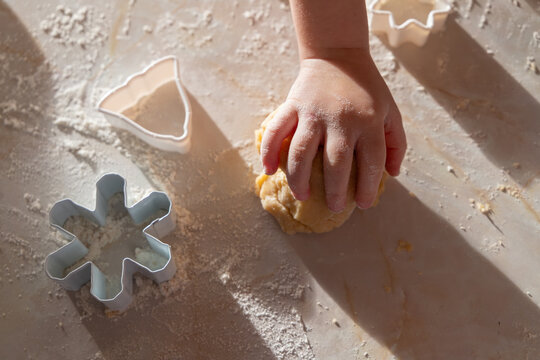 A family baking scene with children preparing German-style cut-out cookies. Little hands working with flour, dough, and festive cookie cutters.