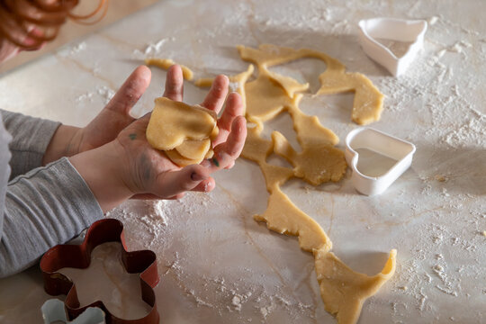 A family baking scene with children preparing German-style cut-out cookies. Little hands working with flour, dough, and festive cookie cutters.