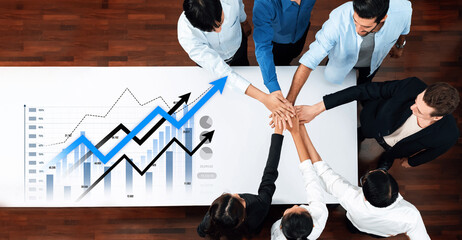 A group of professionals participating in a meeting with hands joined together over a business graph. This image symbolizes teamwork, collaboration, and success in a workplace setting. Scalp