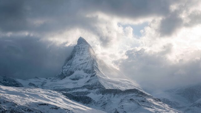 Landscape photograph of a snowy mountain peak. the peak is covered in a thick layer of snow and is surrounded by a cloudy sky.
