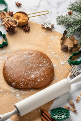 Preparation of gingerbread Christmas cookies. Raw dough and baking tools, rolling pin, various cutters and ingredients on white marble table background