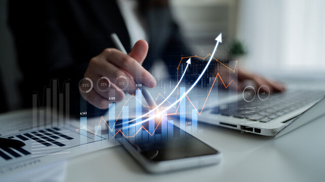 A business professional analyzes financial data on a laptop while using a smartphone, showcasing dynamic graphs to illustrate growth trends and strategies for success. Scalp