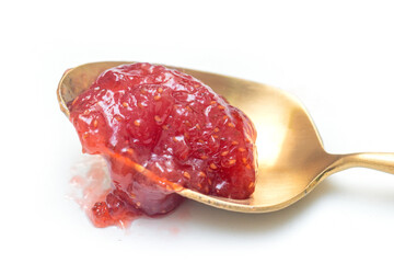 chunky red raspberry jam resting on a vintage gold-toned spoon. The preserves show seeds and texture, isolated on a clean white background. Perfect for food, breakfast, and sweet concepts.