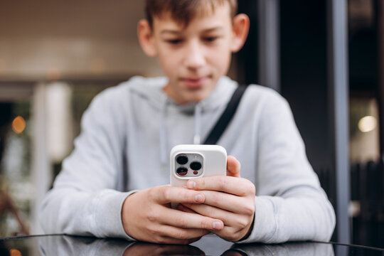 Close-up of teen boy holding smartphone concept of gadget addiction.