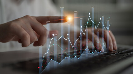 A business professional interacts with digital graphs and charts on a laptop, showcasing financial data analysis and market trends in a modern workspace setting. Scalp