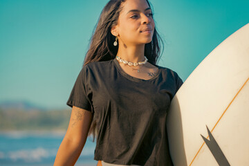 Portrait of an ethnic Surfer Woman holding a surfboard