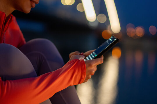 Woman using smartphone at night with blurred city lights in background