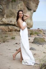 Woman standing on beach wrapped in soft white blanket
